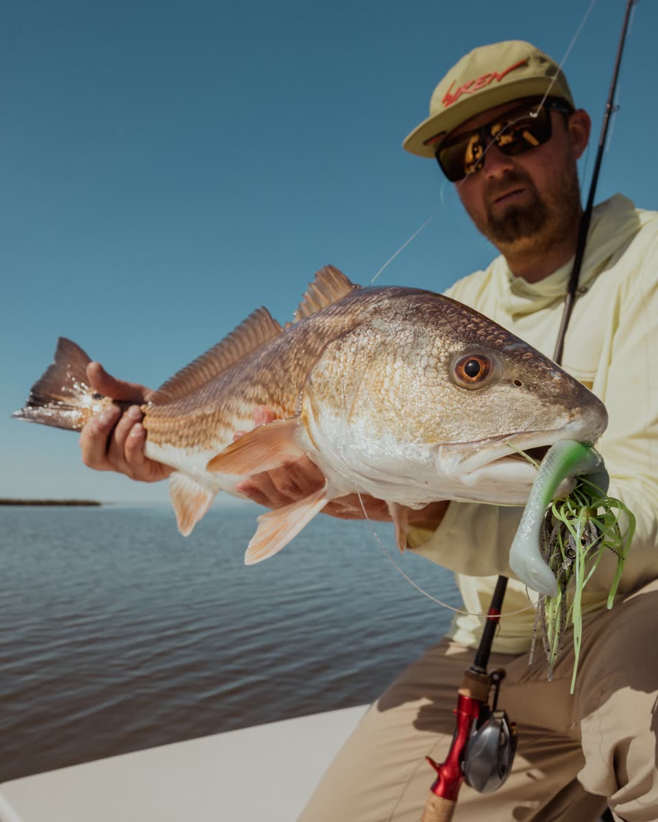 Captain Luke Lowery holding a redfish on the marsh