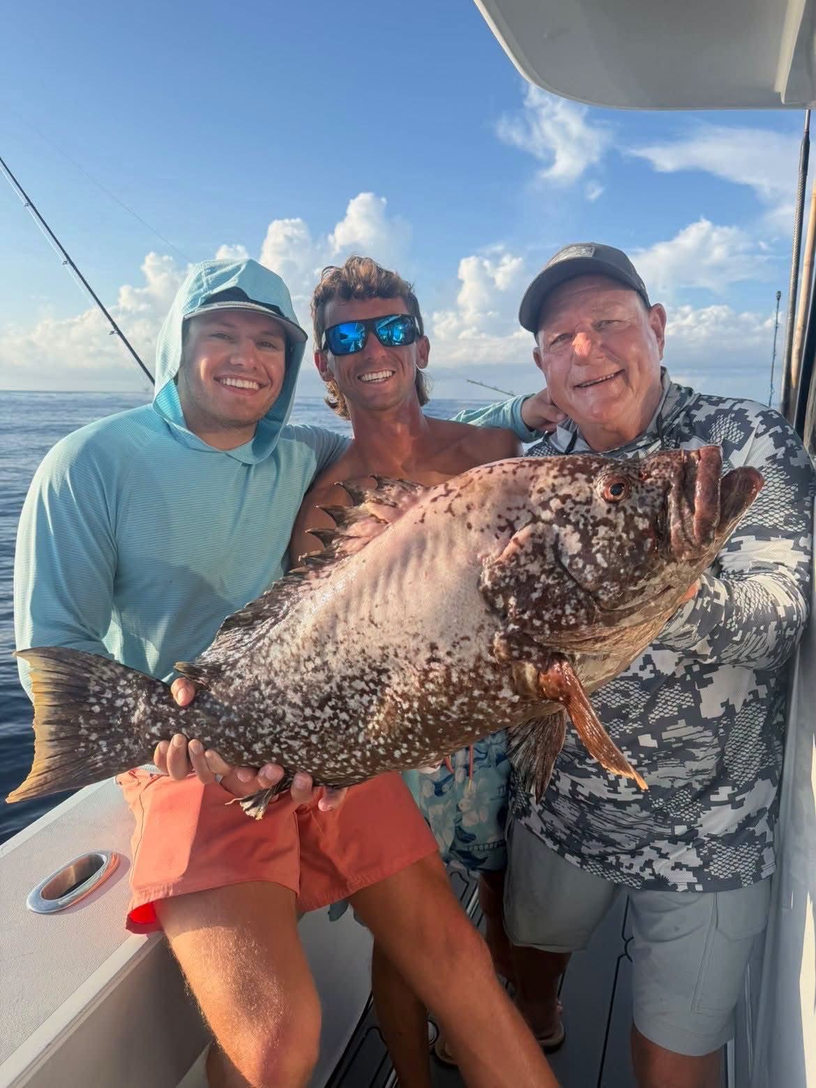 Smiling anglers with a grouper on a DTB trip